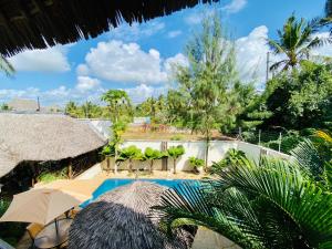a resort with a swimming pool with umbrellas and trees at The Oasis Villa in Diani Beach