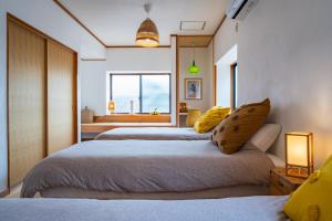 1 dormitorio con 2 camas y ventana en Naoshima Juju Art House　直島ジュジュアートハウス, en Naoshima