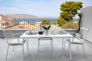 Biały stół i krzesła z widokiem na ocean w obiekcie Maison Poème - Luxury Apartments w mieście Aiándion