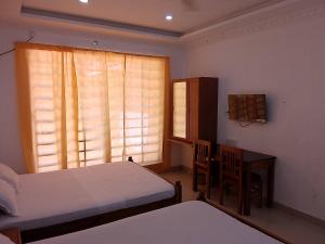 a bedroom with two beds and a desk and a window at Somatheertham Ayurvedic Resort in Trivandrum
