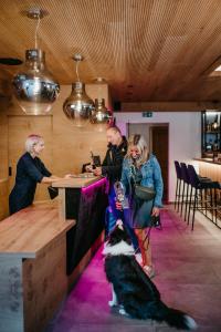 Un uomo, una donna e un cane in un bar di ALMHOF Alpin Apartments & Spa a Dienten am Hochkönig