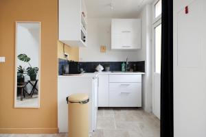 a kitchen with white cabinets and a trash can at La petite maison in Neuville-aux-Bois