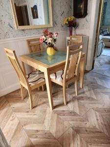 una mesa de madera con sillas y un jarrón con flores. en Captivating 2-Bed ground floor Apartment in Largs en Largs