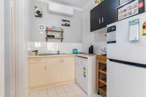 a kitchen with white cabinets and a refrigerator at Lovely "Driftwood Taft" Apartment Beach & Everything few Minutes walk! Central Glenelg in Glenelg