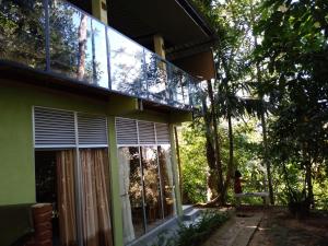 a house with a balcony with windows and trees at Sinharaja Kurulu Ella Eco Resort in Deniyaya