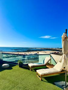 a swimming pool with two lounge chairs and the beach at Villa Bruno con vistas al mar, primera línea de playa in El Cotillo