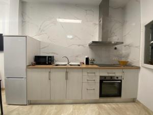 a white kitchen with a sink and a refrigerator at Apartamento La Mamola in La Mamola