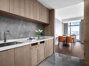 a kitchen with a sink and a table with orange chairs at Cordis, Xuzhou in Xuzhou