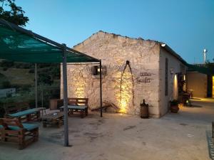 um edifício de pedra com mesas e bancos à sua frente em Casa Giufà B&B em Chiaramonte Gulfi