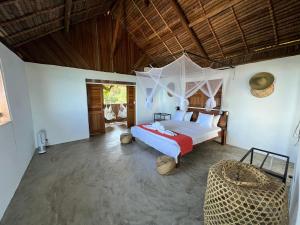 a bedroom with a bed and a chair in a room at Canopee Lodge in Nosy Komba
