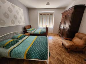 1 dormitorio con 2 camas y 1 silla en Gîte43, en Decazeville