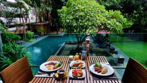 a table with plates of food next to a swimming pool at Aspira 12th Avenue Asoke Sukhumvit in Bangkok
