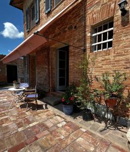 un patio con mesa y sillas y un edificio de ladrillo en Casa Ezio Marchi - Tre spaziose suite, en Bettolle