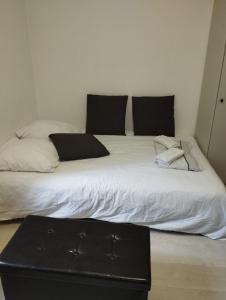 um quarto com 2 camas com lençóis brancos e almofadas pretas em Appartement Brest Saint Martin em Brest