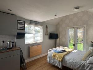 a bedroom with a bed and two windows and a kitchen at The Annexe in Waltham