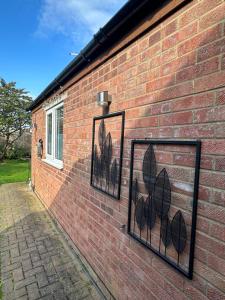 a brick wall with three pictures of leaves on it at The Annexe in Waltham