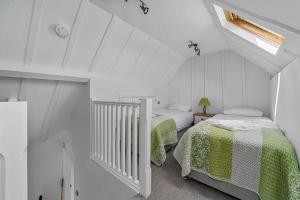 a white attic bedroom with two beds and a window at The Stables Rectory Farm in Halstead
