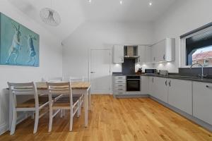 a kitchen with white cabinets and a table and chairs at The Stables Rectory Farm in Halstead