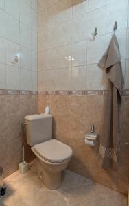 a bathroom with a toilet and a tiled wall at Sea Garden Plaza Apartment in Burgas City