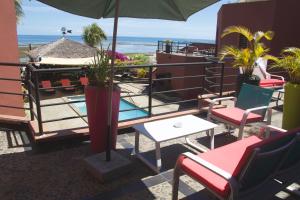 a patio with chairs and tables and an umbrella at H&ocirc;tel R&eacute;sidence Sarimanok in Ambatoloaka