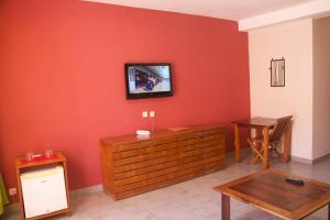 a living room with a tv on a red wall at Hôtel Résidence Sarimanok in Ambatoloaka