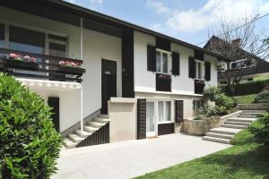 Casa blanca con ventanas con persianas negras y escaleras en Apartments Villa AnnaMaria, en Bled