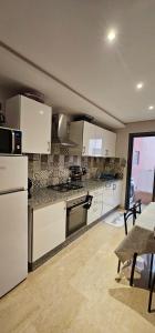 a kitchen with white appliances and a table and chairs at family apartment with swimming pool air conditionning and elevator in Marrakech