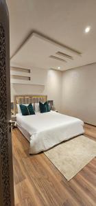 a bedroom with a large white bed with blue pillows at family apartment with swimming pool air conditionning and elevator in Marrakech +17 photos