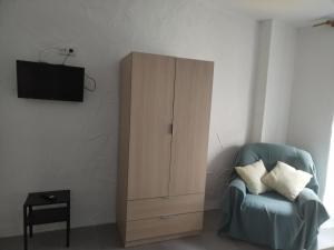 a living room with a blue chair and a cabinet at Apartamentos La Campana 1 in Jerez de la Frontera