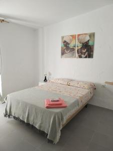 1 dormitorio con 1 cama con 2 cuadros en la pared en Apartamentos La Campana 1, en Jerez de la Frontera
