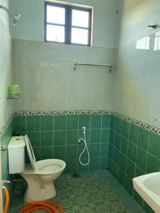 La salle de bains est pourvue de carrelage vert, de toilettes et d'un lavabo. dans l'établissement Sri Panorama Home, à Kota Bharu