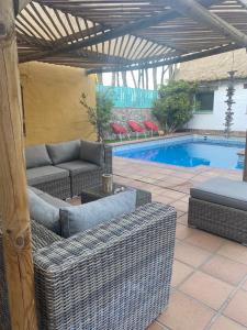 un patio con muebles de mimbre y una piscina en Casa Rural Los Pepe Sancti Petri, en Chiclana de la Frontera