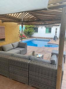 un patio con sofá, sombrilla y piscina en Casa Rural Los Pepe Sancti Petri, en Chiclana de la Frontera