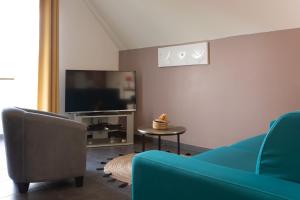 sala de estar con sofá azul y TV en Leu Corail, en Saint-Leu
