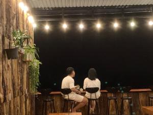 un hombre y una mujer sentados en un bar en Rừng Phố Homestay And Coffee, en Kon Plong