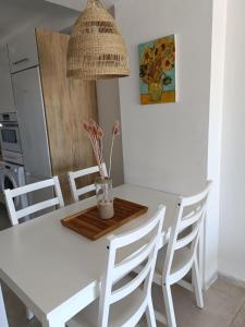 una mesa de comedor blanca con sillas y un jarrón con flores en Casa adosada Rompeolas-Atlanterra, en Zahara de los Atunes