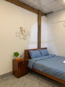Un dormitorio con una cama con sábanas azules y una mesa. en Rừng Phố Homestay And Coffee, en Kon Plong