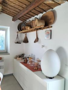 a kitchen with white cabinets and a shelf on the wall at Casa Giufà B&B in Chiaramonte Gulfi