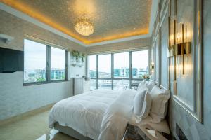a bedroom with a large bed with white sheets and windows at Ritz Residence @ Imago Loft B 7th Floor in Kota Kinabalu