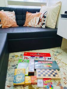 a pile of books sitting on the floor in front of a couch at 1 Br CONDO Vine Residences Quezon City with POOL NETFLIX WIFI VIDEOKE BOARD GAMES in Manila