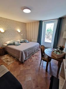 a bedroom with a bed and a table and a window at La Jacquière in Chaumont-sur-Loire