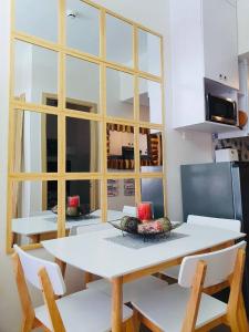 1 Br CONDO Vine Residences Quezon City with POOL NETFLIX WIFI VIDEOKE BOARD GAMES في مانيلا: غرفة طعام مع طاولة بيضاء وكراسي بيضاء