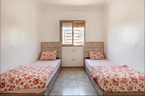 twee bedden in een kamer met witte muren bij Parfaite appartement en résidence in Marrakesh