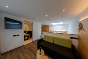 a living room with a couch and a flat screen tv at Hotel Gran Pre in San Vigilio Di Marebbe