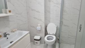 Baño blanco con aseo y lavamanos en Luxury New and Modern Apartments, en Mamaia Nord – Năvodari