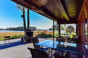 a patio with a table and chairs and a lake at Bebrusų sodyba in Molėtai