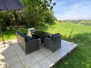 un patio con 2 sillas y una mesa con sombrilla en Le Manoir aux Volets Verts, en Salerm