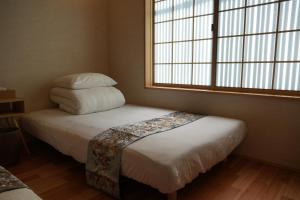 ein Schlafzimmer mit einem Bett mit zwei Kissen und einem Fenster in der Unterkunft Kyoto-cocoro house in Kyoto