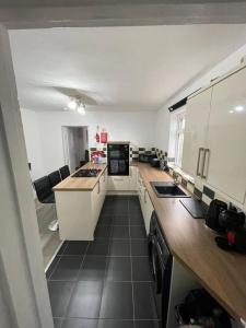 uma cozinha com armários brancos e piso em azulejo preto em Luxury Spacious 2-Bed House in Brentwood Essex em Brentwood