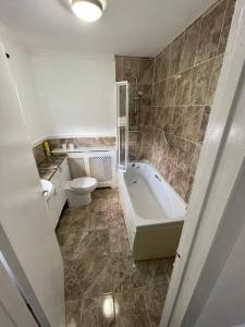 a bathroom with a tub and a toilet and a sink at Luxury Spacious 2-Bed House in Brentwood Essex in Brentwood